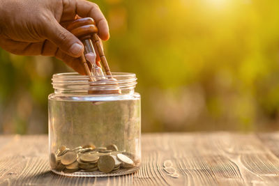 Close-up of hand holding glass jar on table