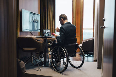 Disabled businessman with colleagues on video conference in office during pandemic