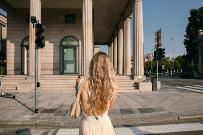 Rear view of woman standing on street against buildings