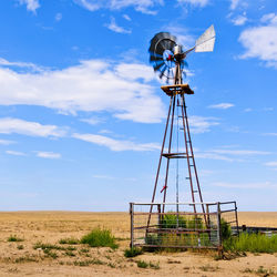 Low angle view of windmill on field against sky