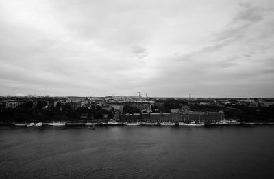 View of city at waterfront against cloudy sky