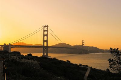 Golden gate bridge over sea against sky during sunset