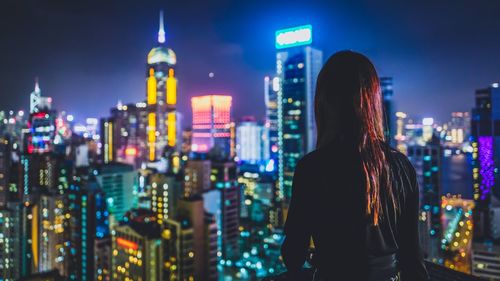 Rear view of women overlooking illuminated cityscape