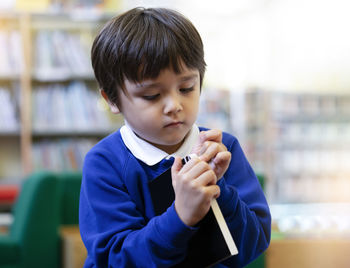 Cute boy holding book in library