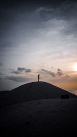 Silhouette person standing on land against sky during sunset
