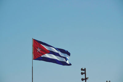 Low angle view of cuban flag against clear blue sky