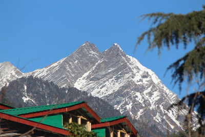 Low angle view of snowcapped mountains against clear blue sky