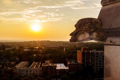 Statue in city against sky during sunset