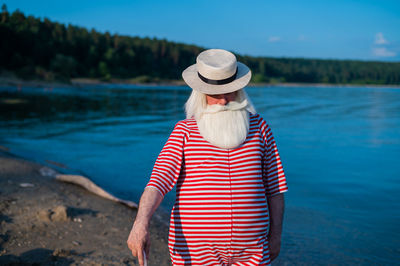 Midsection of woman wearing hat standing at beach