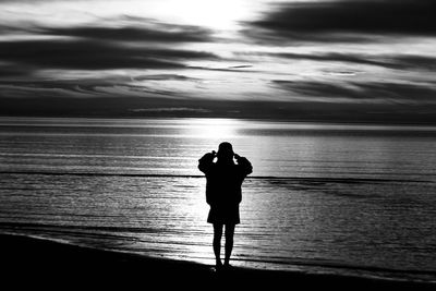 Silhouette of woman standing at beach against sky 