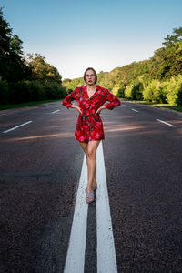 Full length portrait of smiling girl standing on road