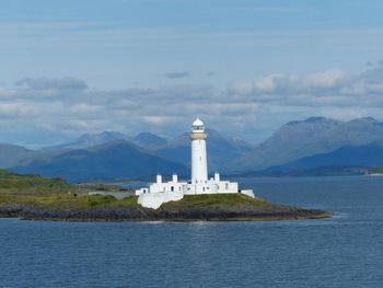 Lighthouse by sea against sky