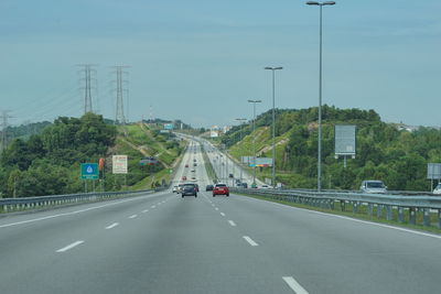 Vehicles on highway against sky in city