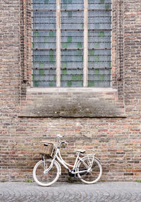 Bicycle parked against brick wall of building