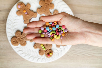 Cropped image of mother hand holding candies over cookies
