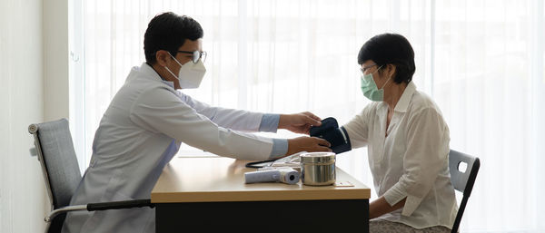 Doctor wearing mask examining patient in clinic