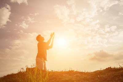 Man standing on field against sky during sunset