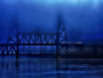 Bridge over river against sky at dusk