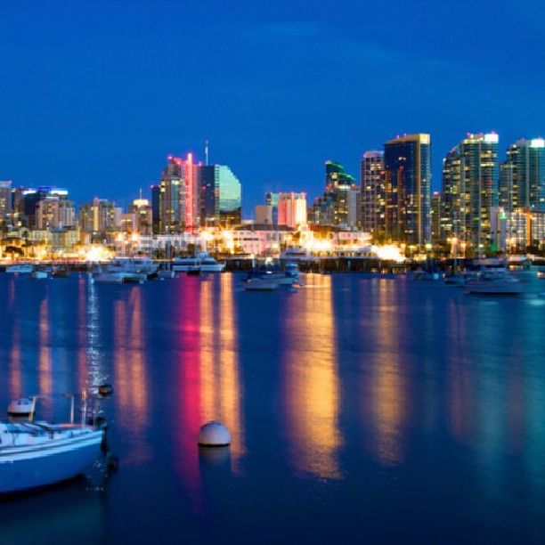 water, nautical vessel, building exterior, city, boat, architecture, waterfront, moored, built structure, transportation, illuminated, mode of transport, harbor, reflection, sea, cityscape, river, skyscraper, clear sky, urban skyline