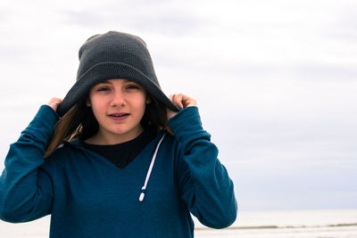 Portrait of smiling woman standing at beach during winter