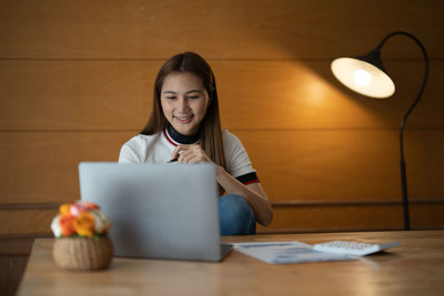 Smiling woman using laptop on table at home