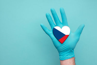 Close-up of hand holding blue over white background