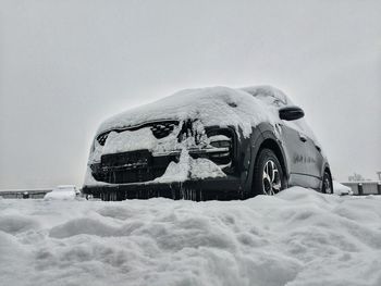Snow covered car against clear sky during winter