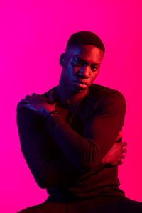 Portrait of young man against pink background