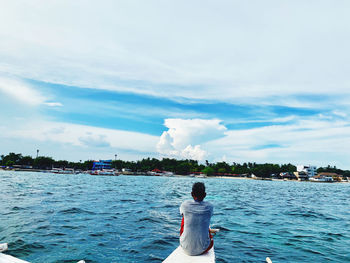 Rear view of man in sea against sky