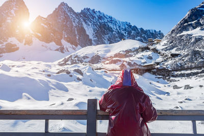 Rear view of woman looking at snowcapped mountains during winter