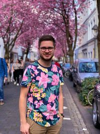 Portrait of woman standing by pink flowers