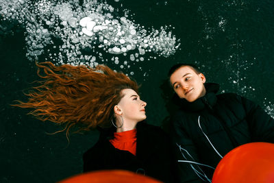 High angle view of couple lying on frozen lake