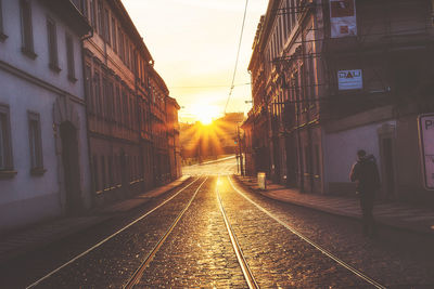 Railroad tracks in city against sky during sunset