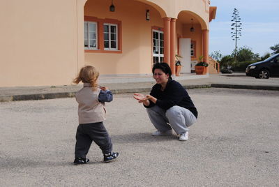 Full length of mother and daughter playing outside house