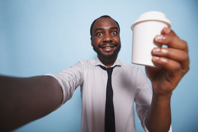 Portrait of young man holding coffee at home