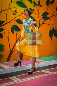 Portrait of female model standing against patterned wall