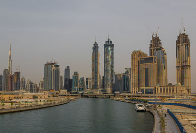 Bridge over river by buildings against sky in city