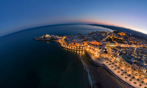 High angle view of city by sea against clear blue sky