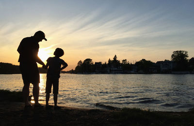 Silhouette couple standing against sky during sunset