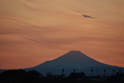 Scenic view of silhouette mountains against orange sky