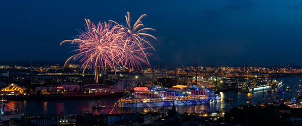 Firework display in city against sky at night