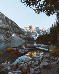 Boats moored at pier on lake against mountain during winter