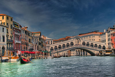 View of canal in city against cloudy sky
