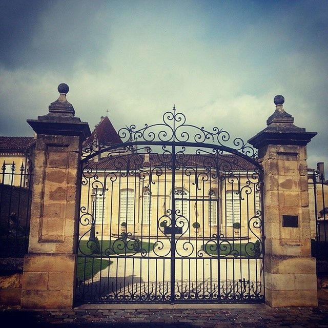 architecture, built structure, building exterior, sky, gate, cloud - sky, graffiti, art, art and craft, low angle view, closed, text, outdoors, creativity, railing, day, entrance, no people, metal, wall - building feature