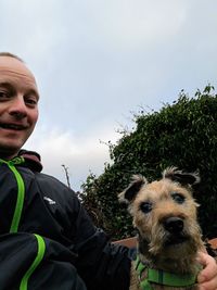 Portrait of man with dog against sky