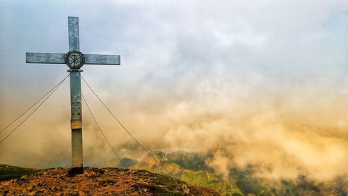 Low angle view of cross on landscape against sky