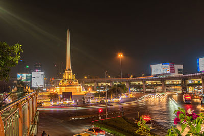 Illuminated city by river against sky