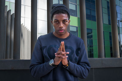 Portrait of young man standing against wall