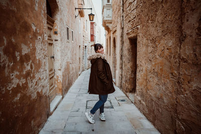 Portrait of young woman walking in alley