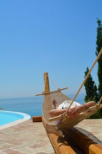 Woman relaxing on hammock against sky